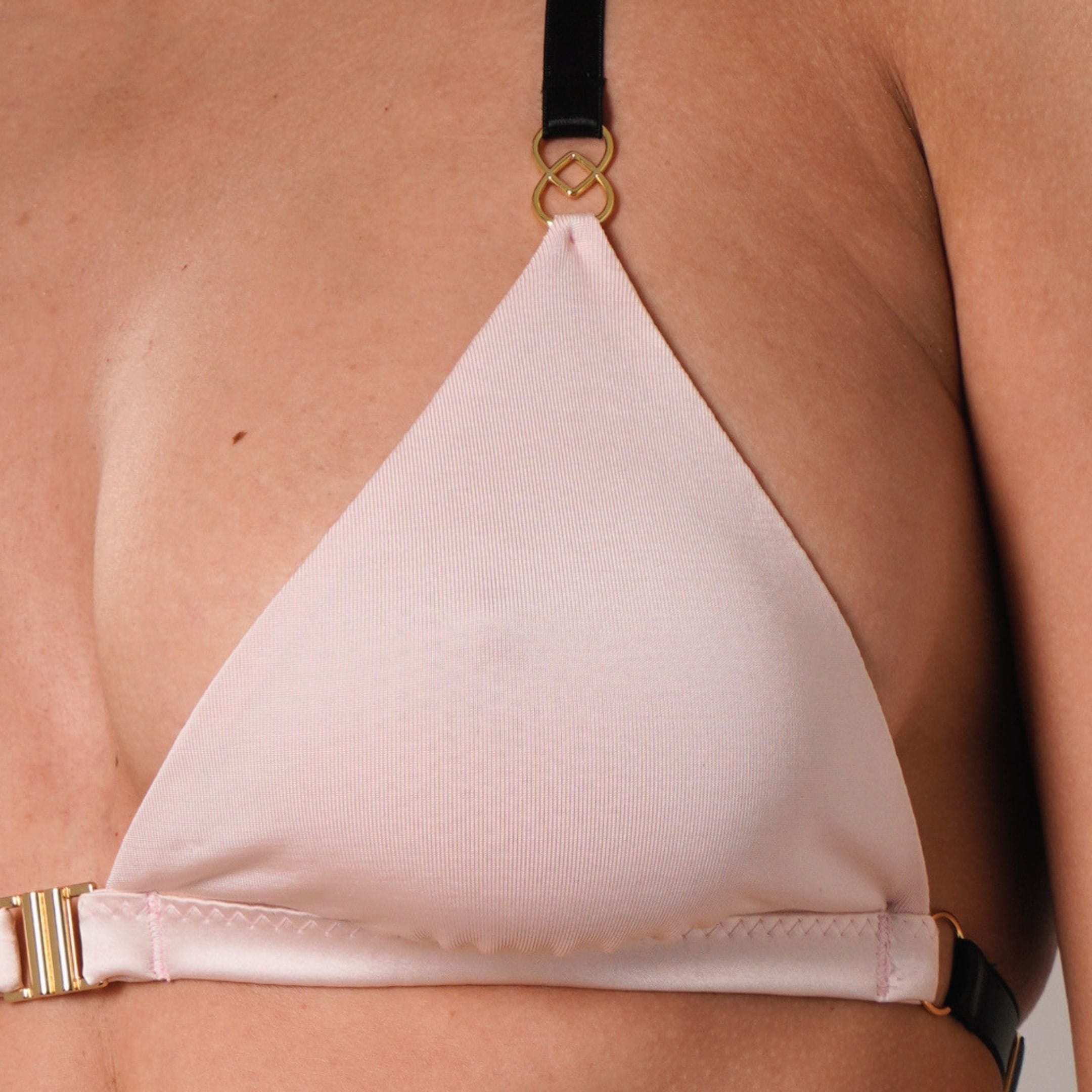 blush pink non wired triangle bralette top worn by a person on a neutral background